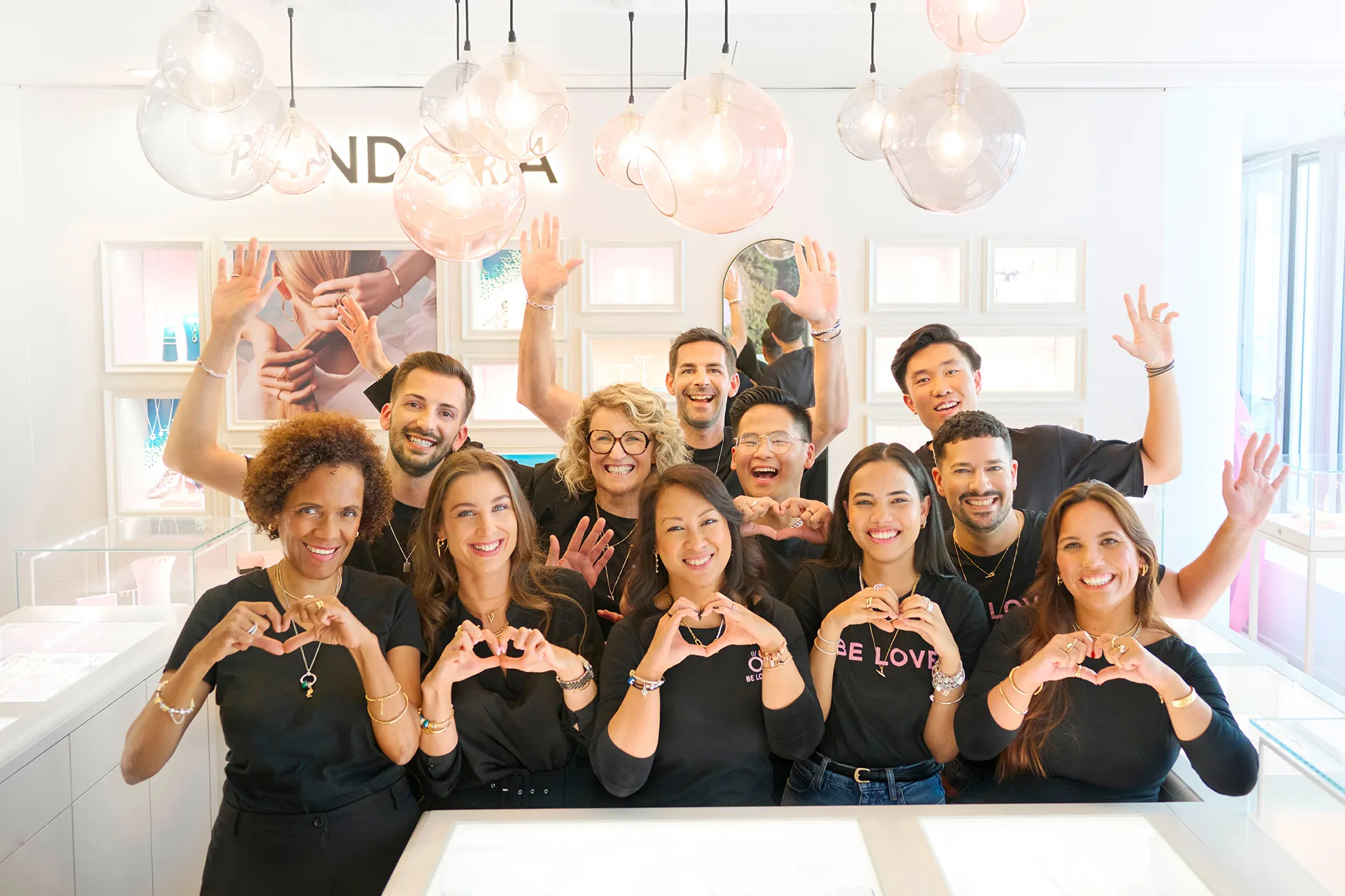 Jewelry store staff smiling and assisting a customer with a bracelet at a counter