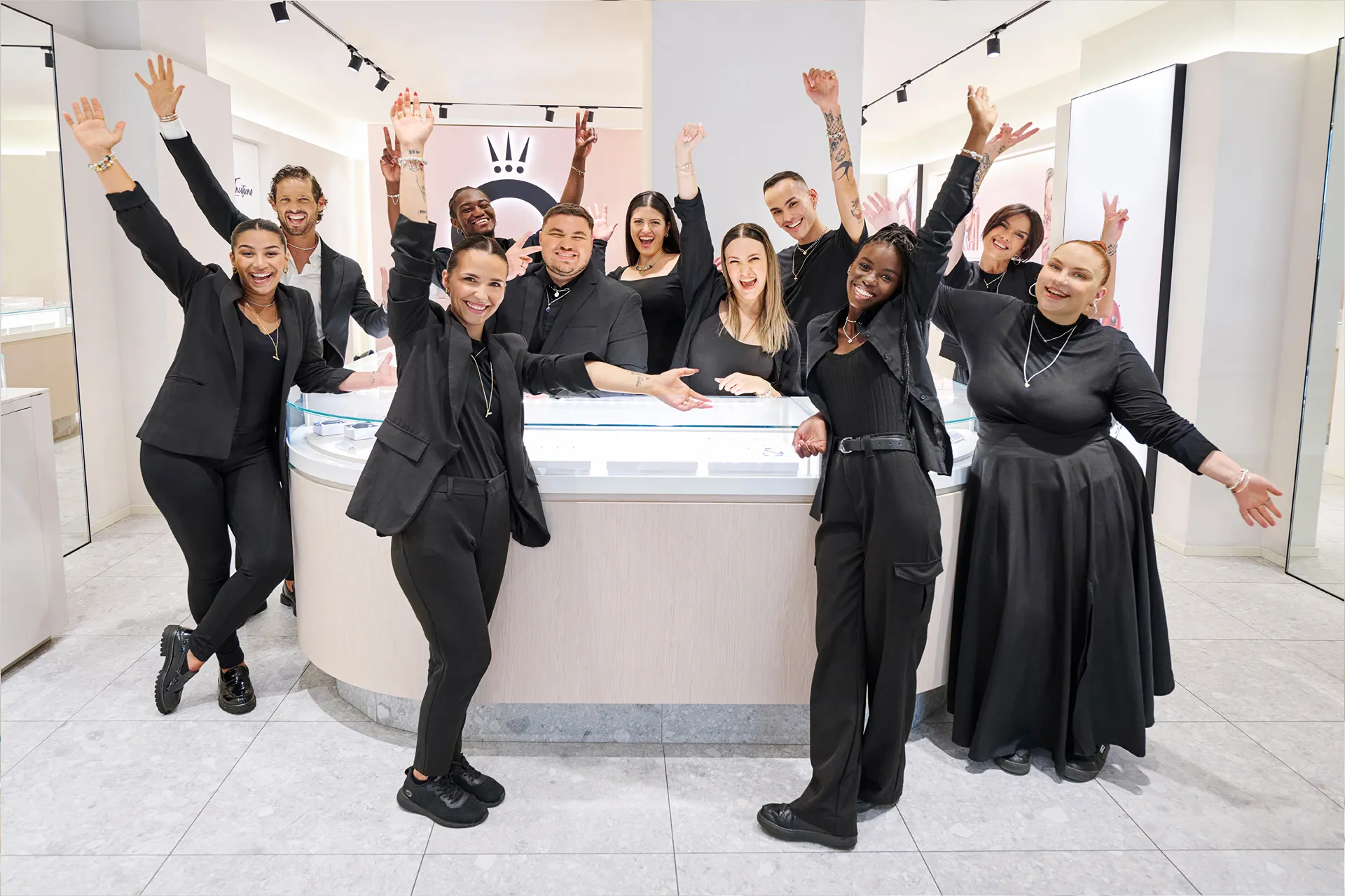 Jewelry store staff smiling and assisting a customer with a bracelet at a counter